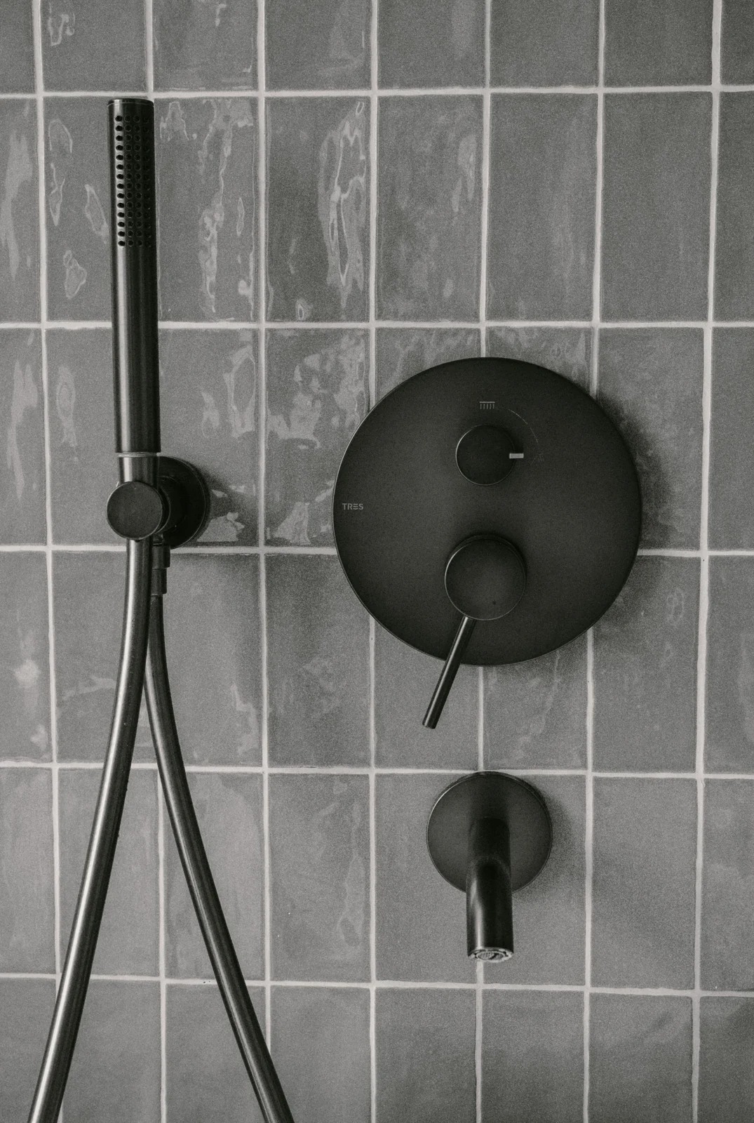 Black shower head against grey tiles