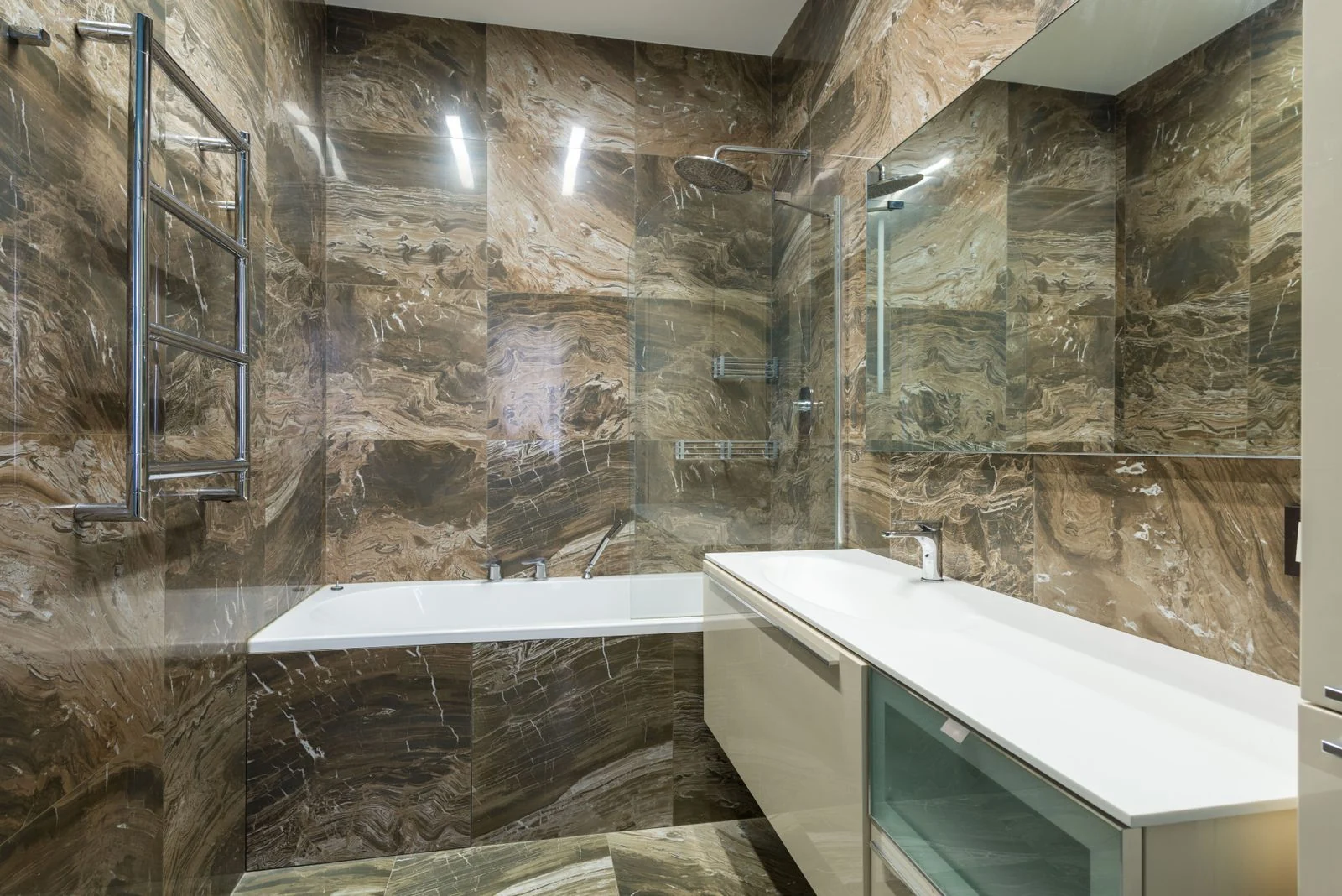 Bath placed near sink on cabinet at wall with mirror in modern light bathroom with heated towel rail at home